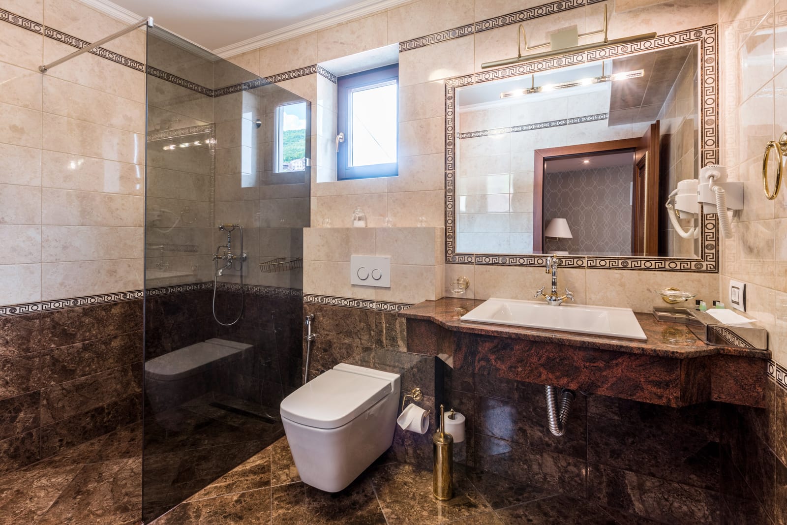 A marble bathroom with walk-in glass shower and framed mirror