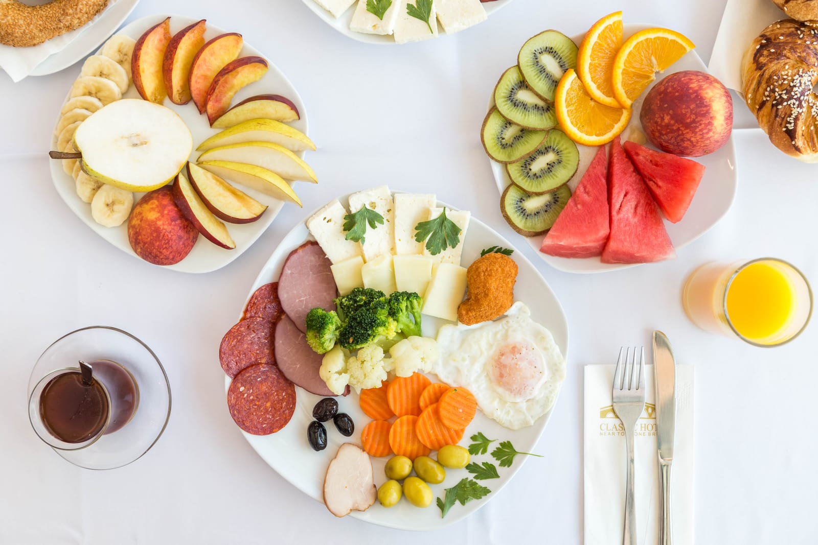Overhead view of a colourful breakfast with fruit, cheese, cured meats and tea