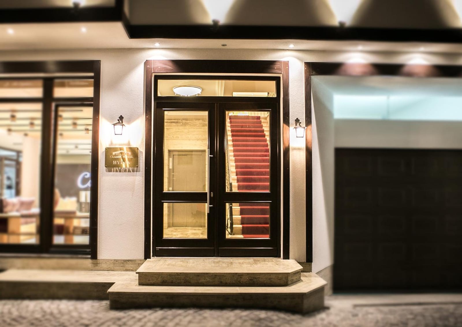 The hotel entrance at night, with a red-carpeted staircase inside