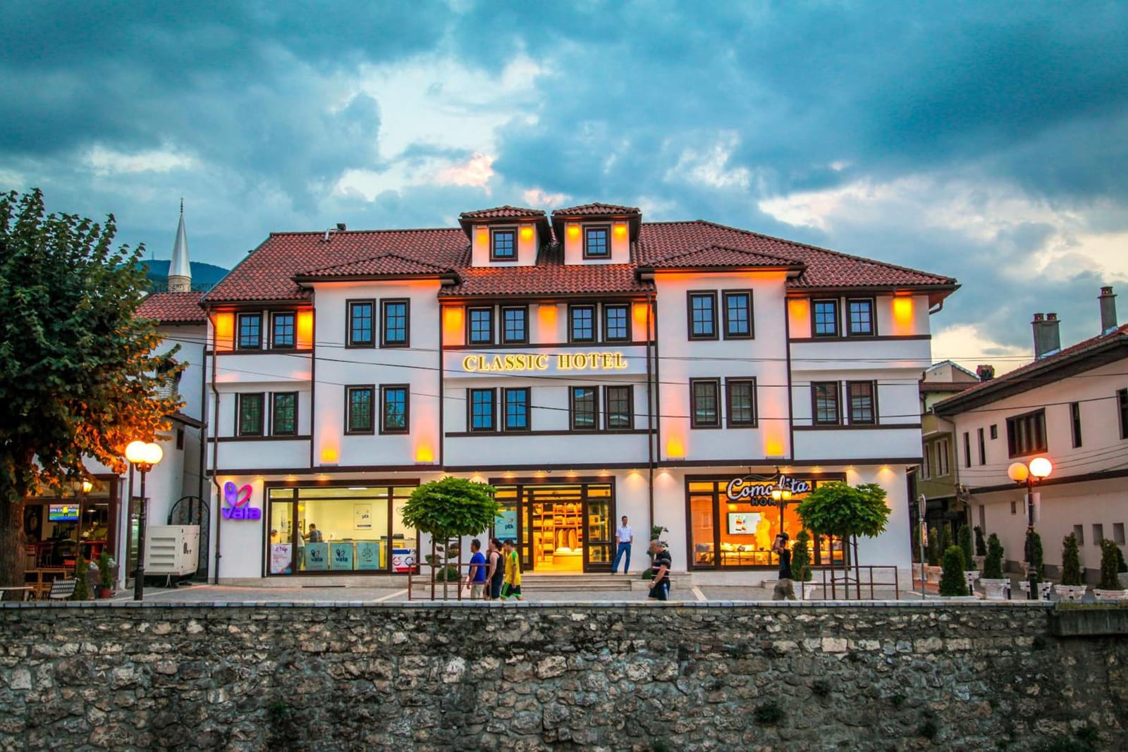 Classic Hotel lit up at dusk on the bank of the Lumbardhi