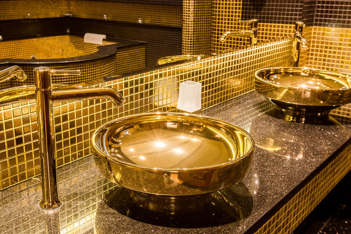 A polished gold vessel basin on black granite