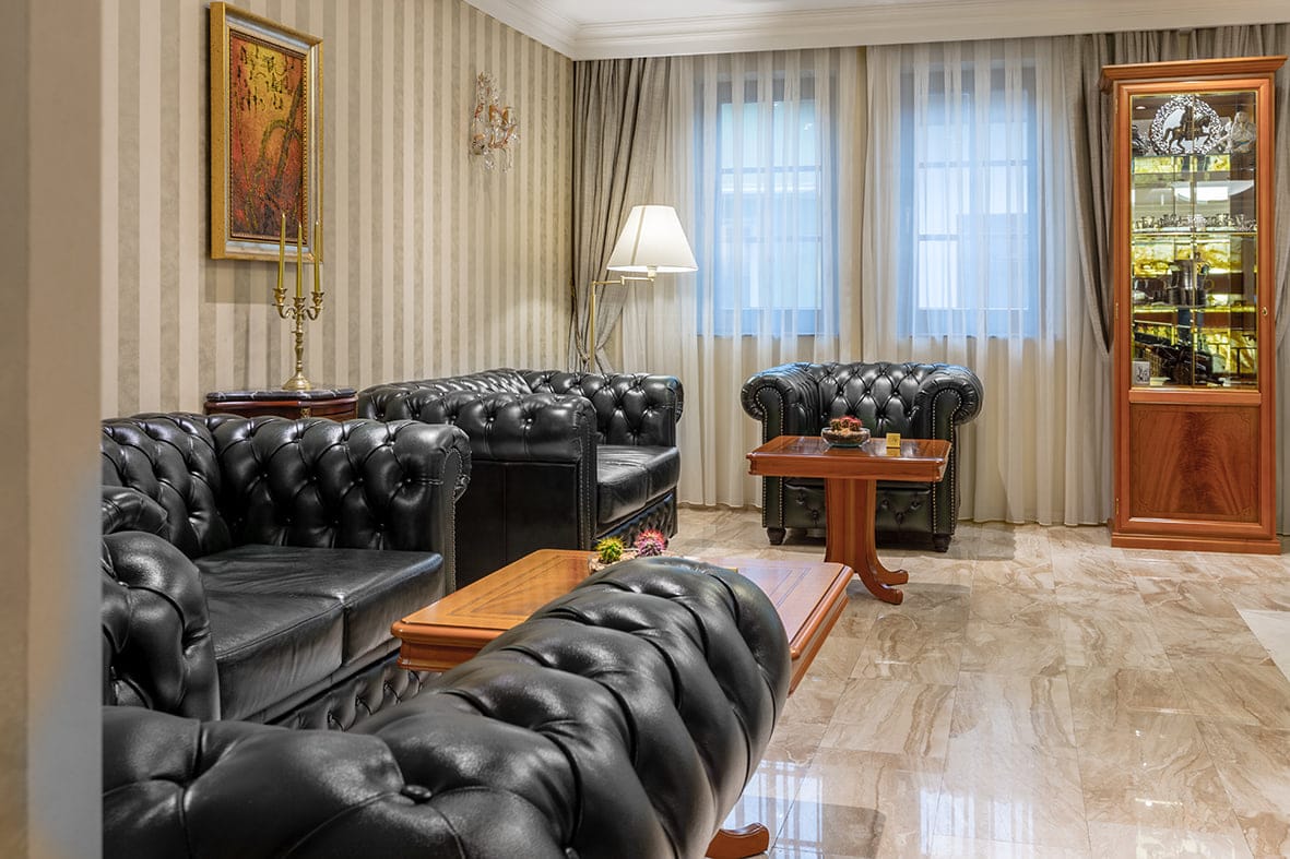 A lounge corner with Chesterfield sofas beneath striped wallpaper