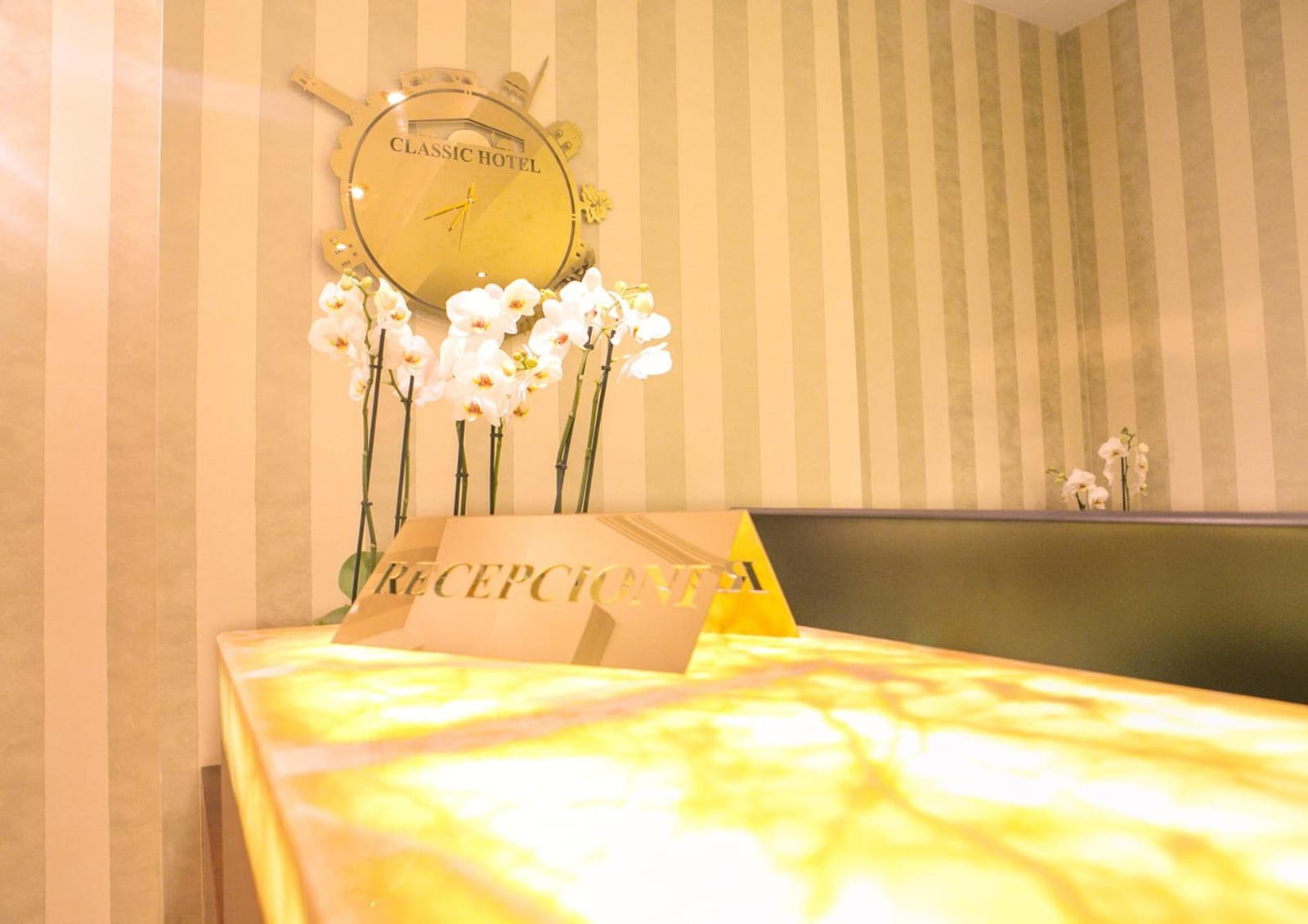 The onyx reception desk with white orchids and the hotel clock