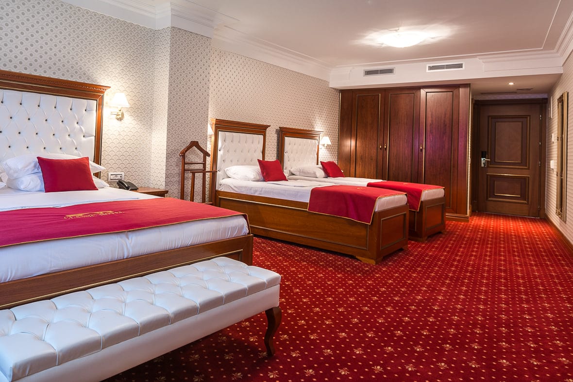 Deluxe Family room with a double bed and two single beds beneath white tufted headboards
