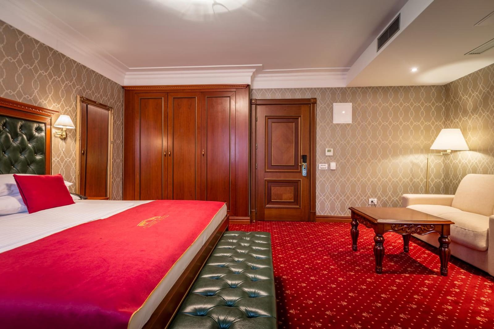 Junior Suite with a green tufted bench, wardrobe and seating area