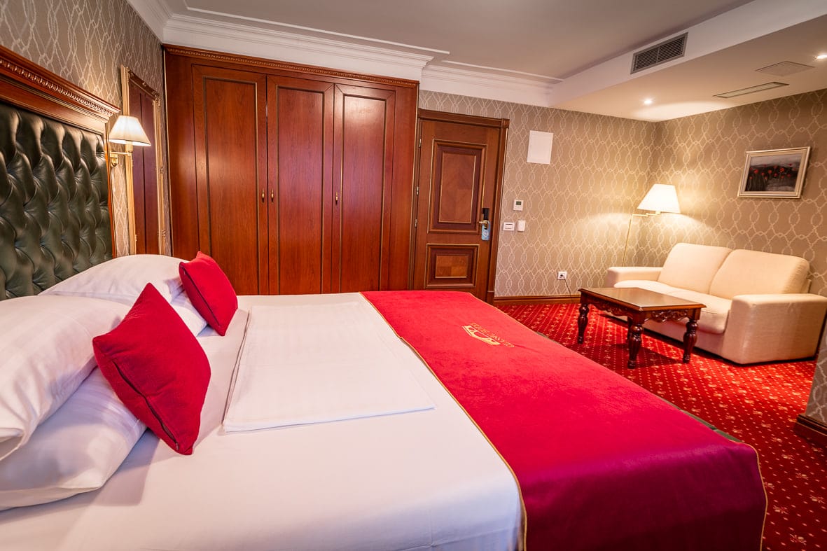 Junior Suite bed with crimson cushions and a separate sofa corner