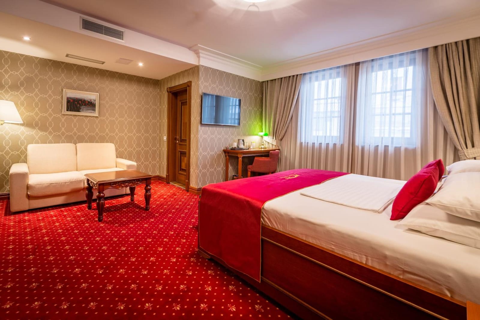 Bright Junior Suite with sofa bed, coffee table and tall windows