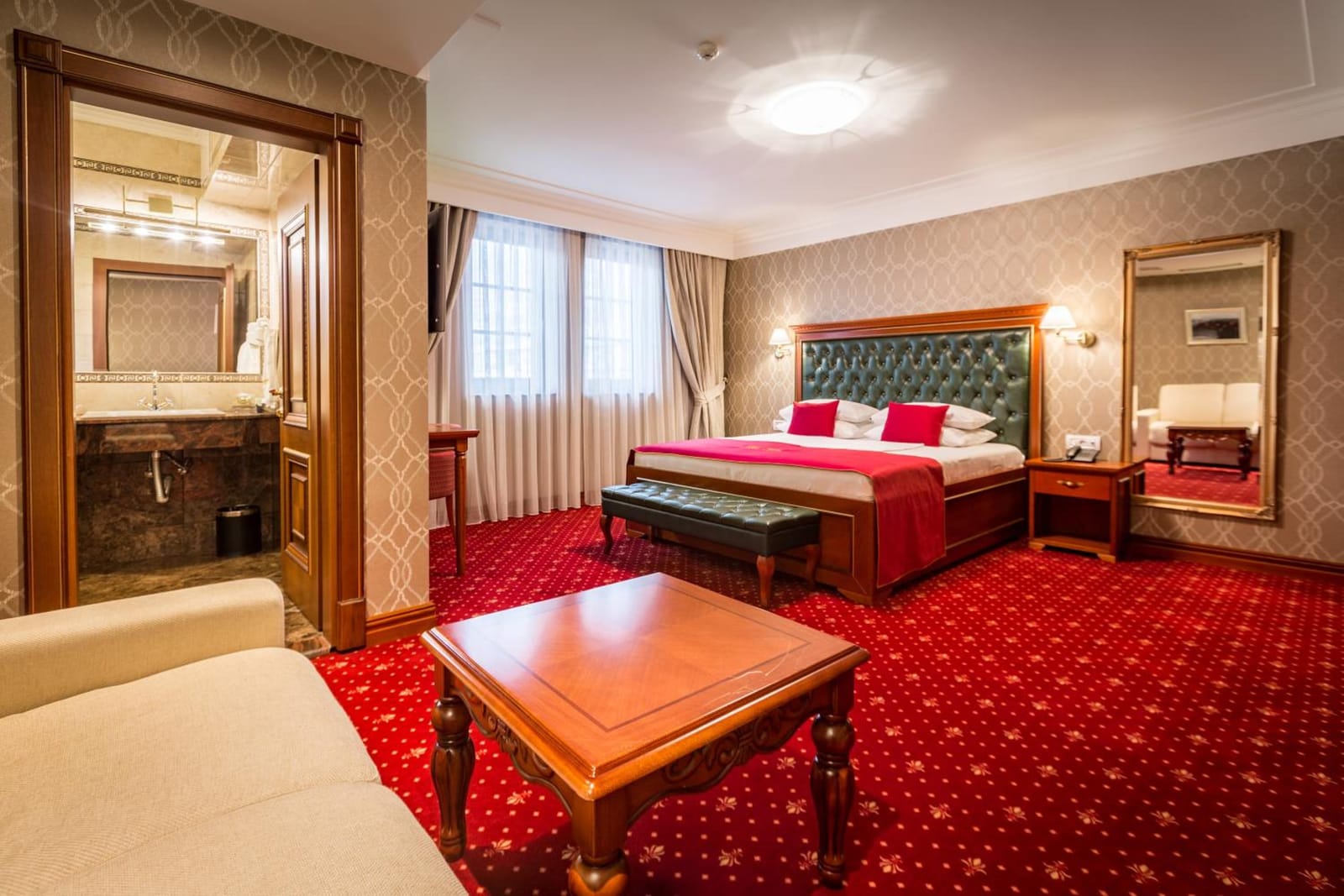 Junior Suite with green leather headboard, sofa, coffee table and marble bathroom