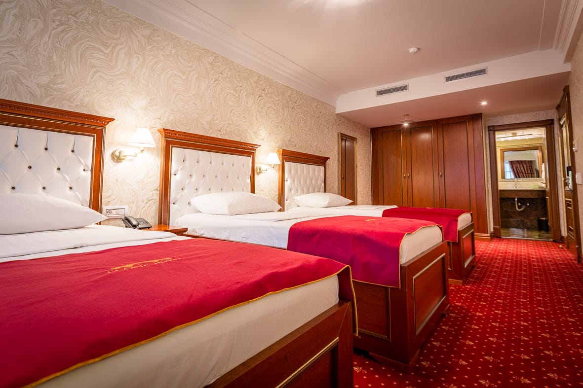 Deluxe Triple room with three single beds, a wardrobe and the en-suite bathroom