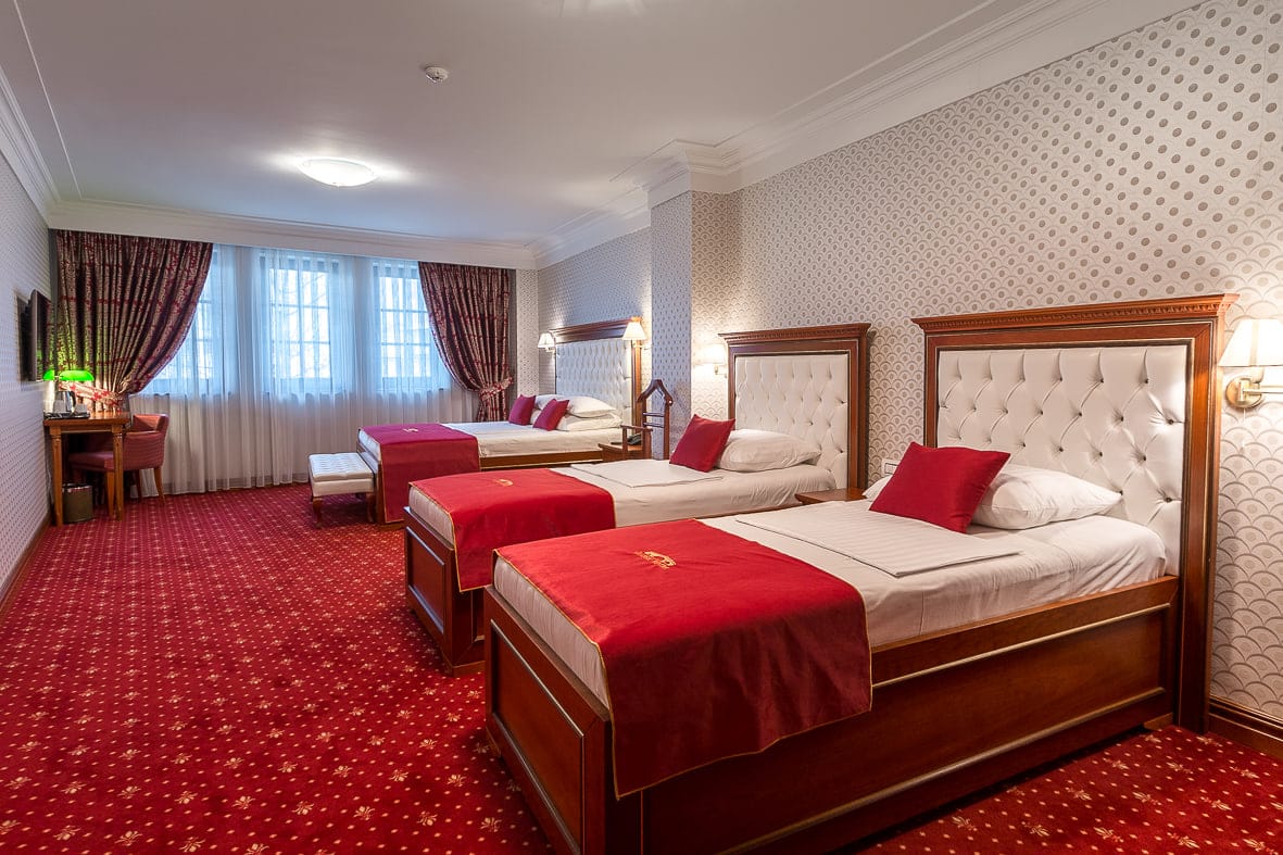 Deluxe Triple room with three single beds and white tufted headboards