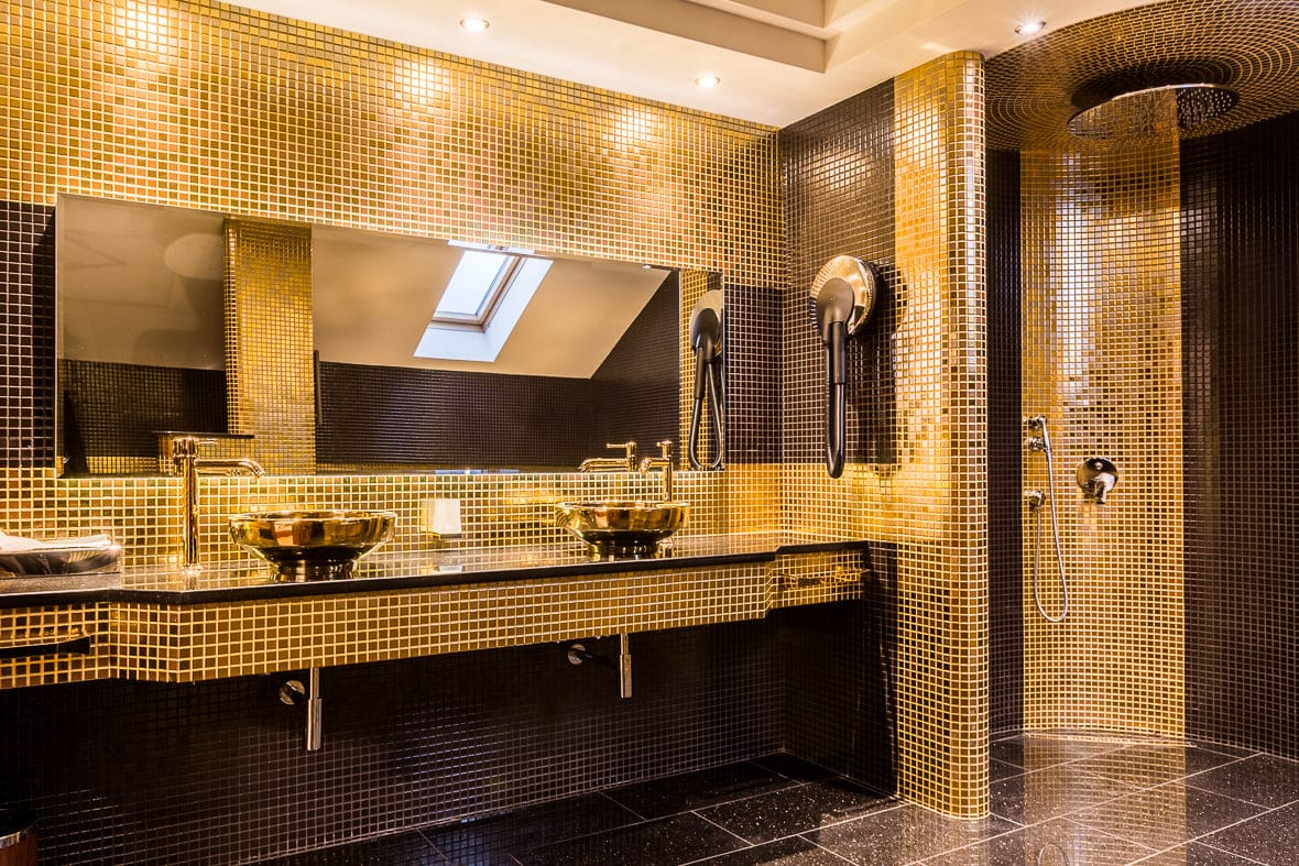 Gold mosaic bathroom with twin gold vessel sinks and rain shower