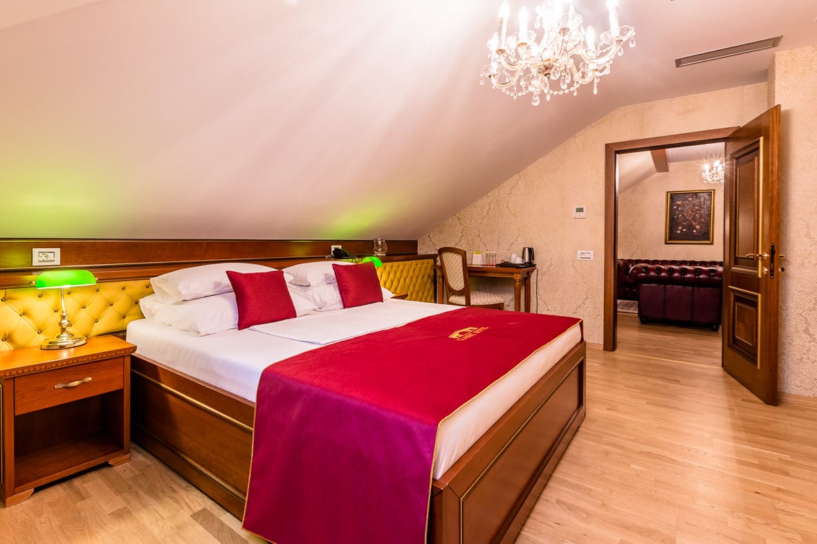 Suite bedroom with golden tufted wall, chandelier and attic ceiling