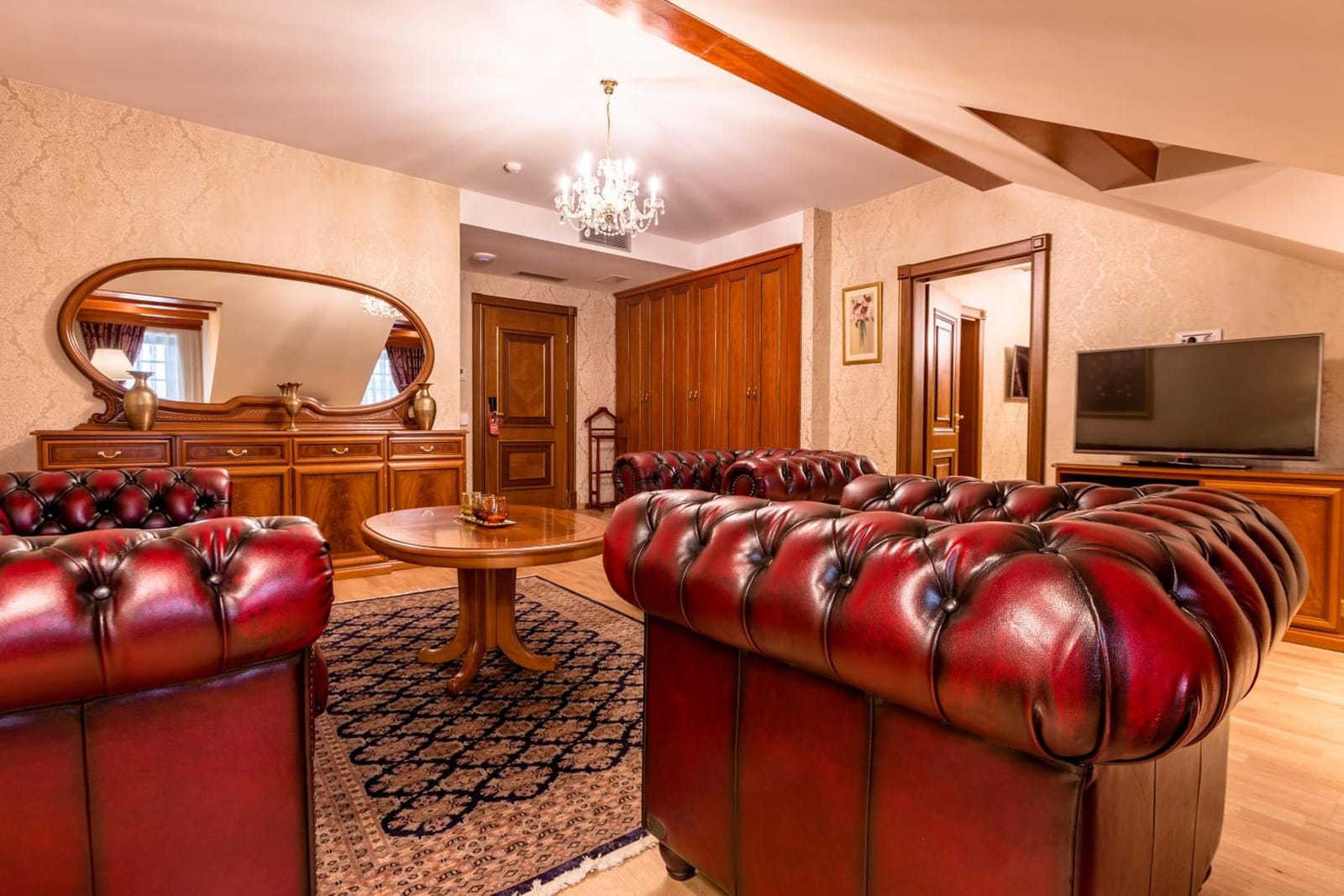 Suite lounge with Chesterfield sofas, oval mirror and TV