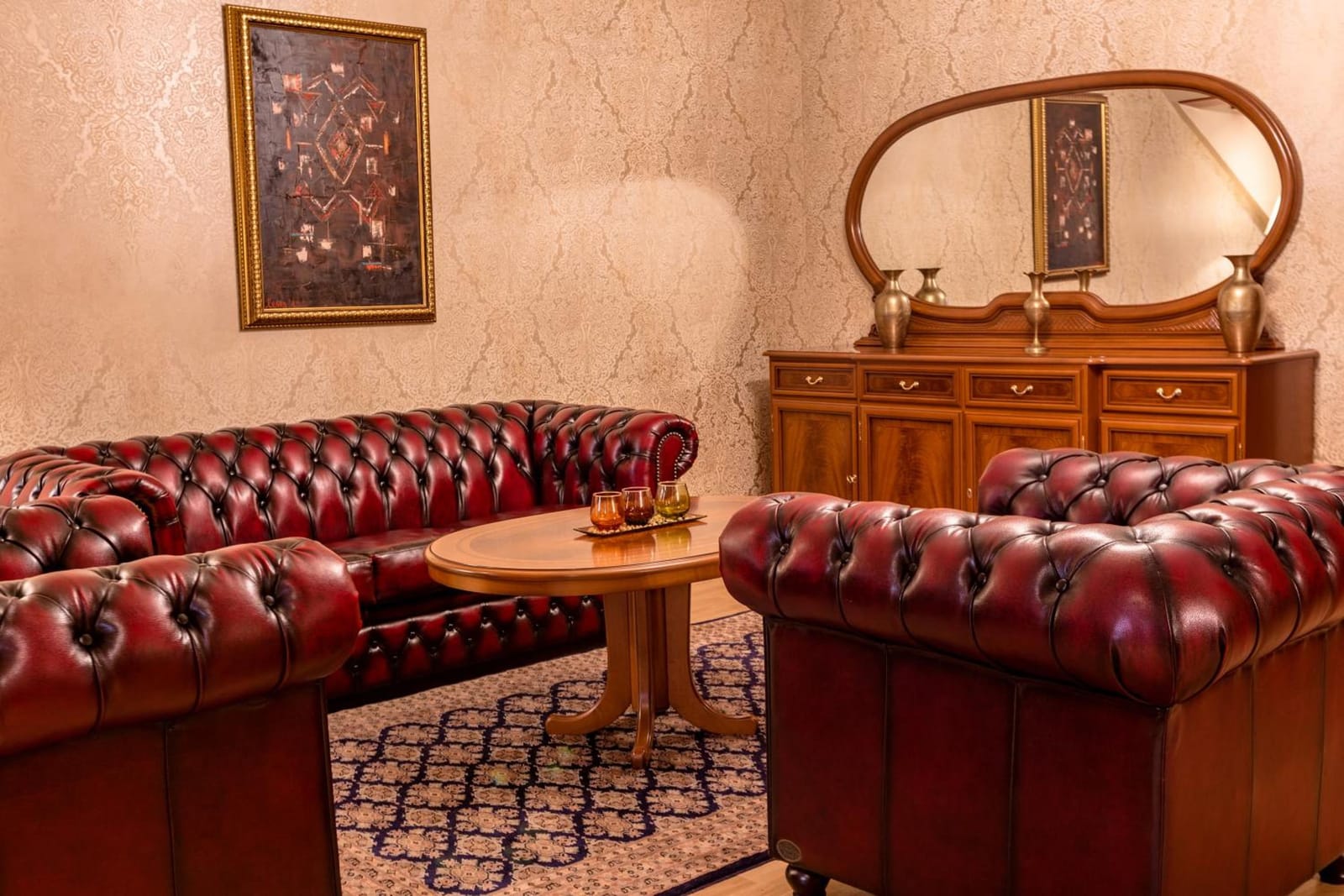 Oxblood leather sofas, a cherry-wood dresser and oval mirror