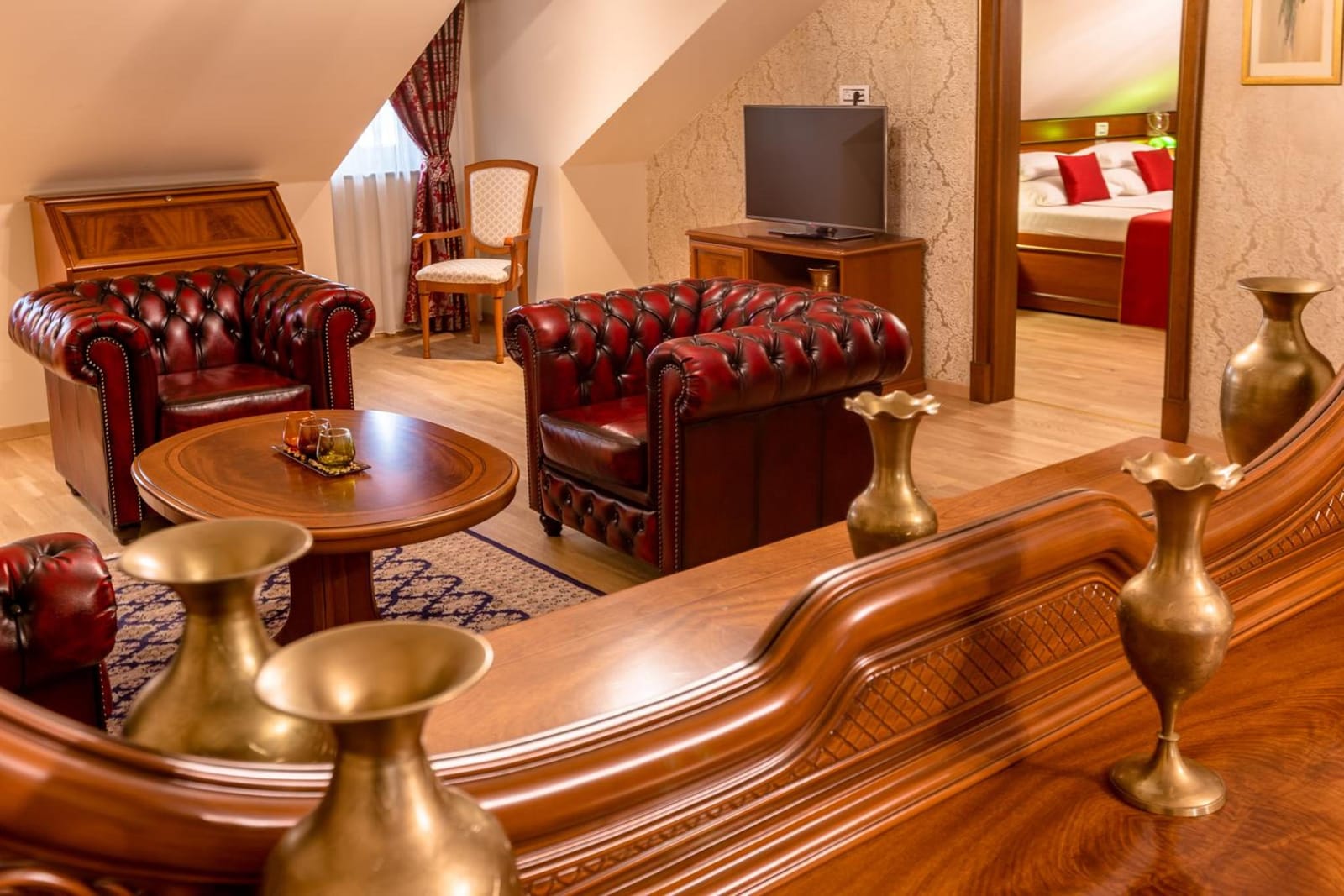 Brass vases and leather armchairs in the suite living room