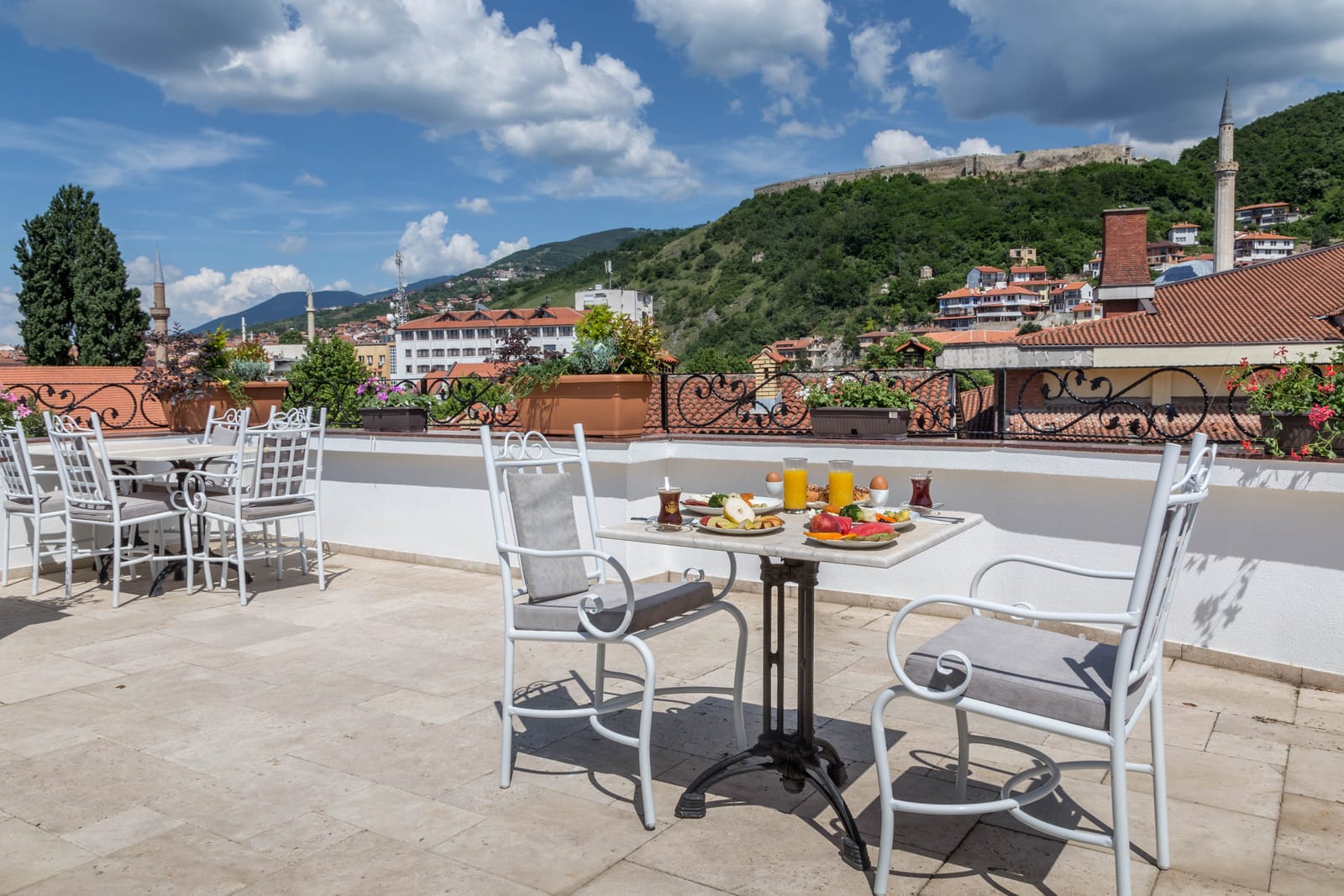 A white wrought-iron table set for breakfast on the rooftop terrace